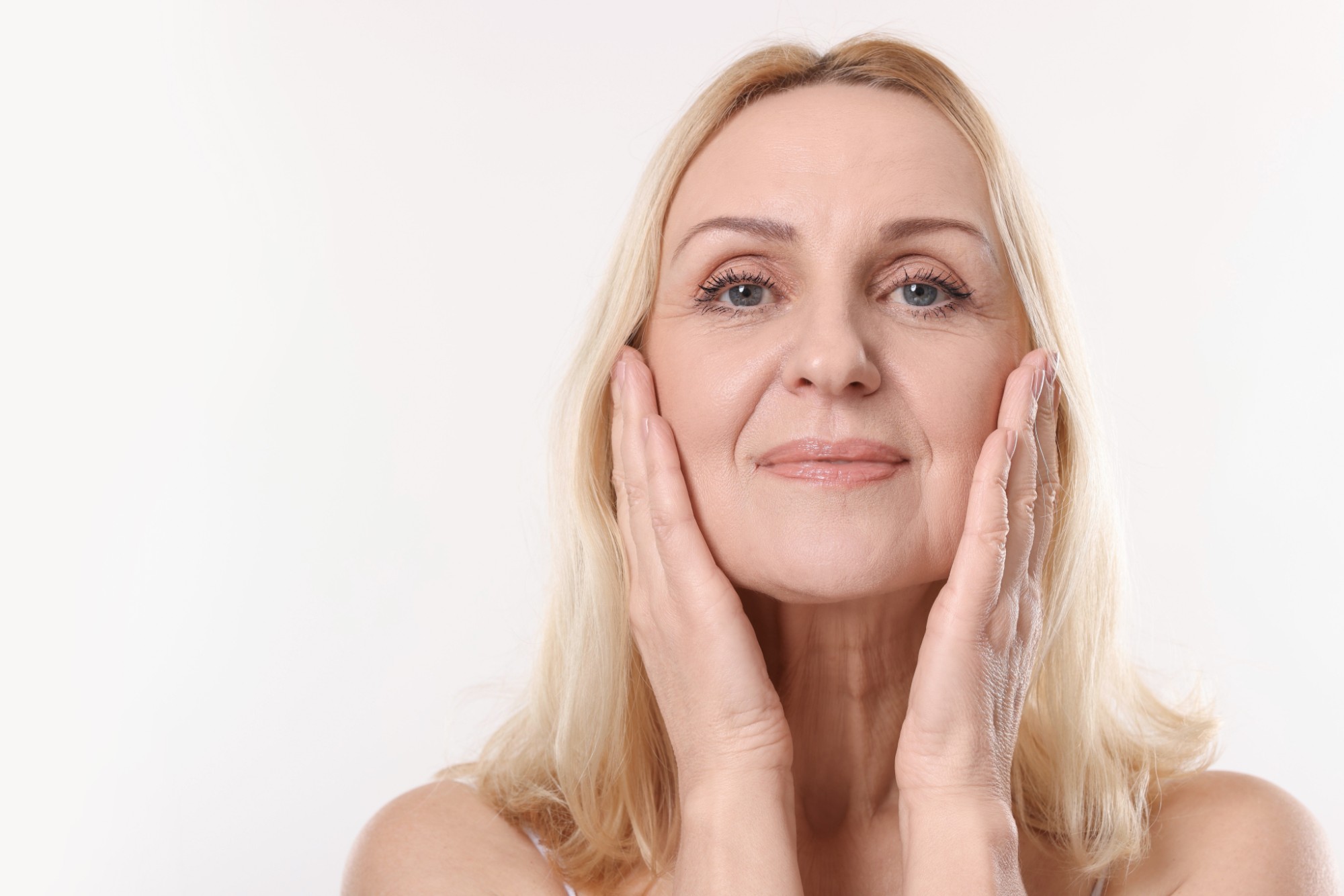 Blonde woman with her hands on her cheeks and a rested look
